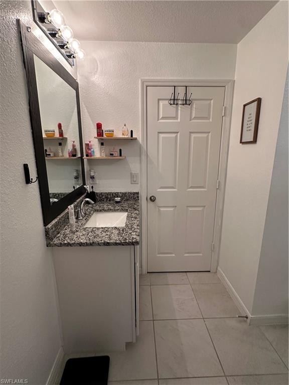 Bathroom vanity featuring a granite countertop, undermount sink, and chrome faucet