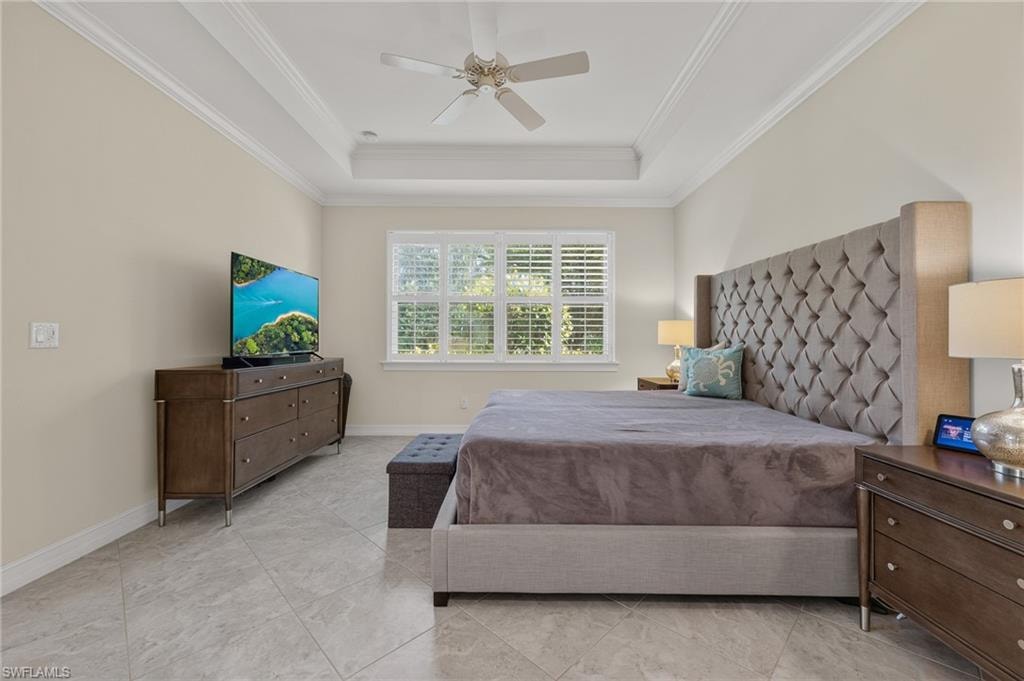 Tray ceiling with crown molding and a ceiling fan, featuring a window with white plantation shutters and light tile flooring