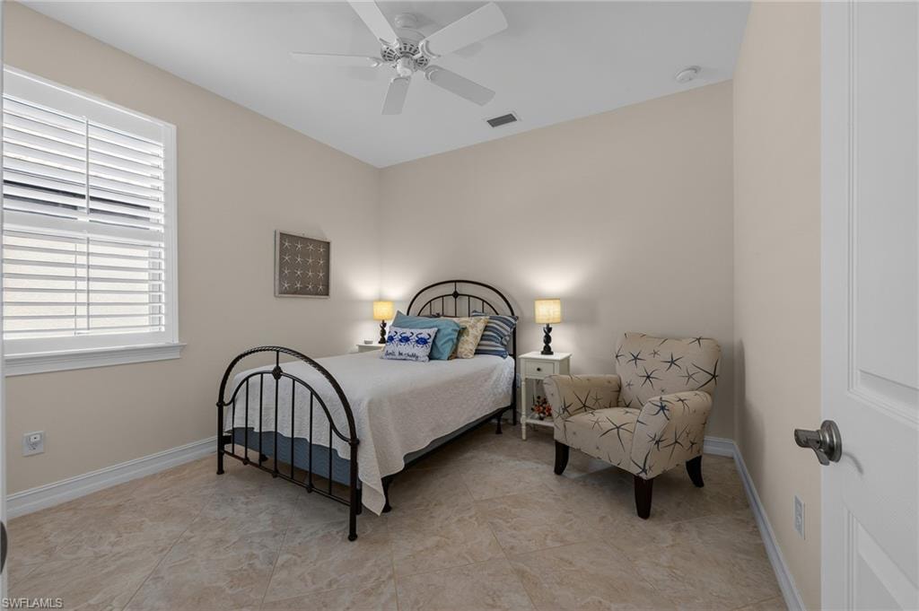 Neutral-toned room featuring large format tile flooring, a window with plantation shutters, a ceiling fan, and white baseboards