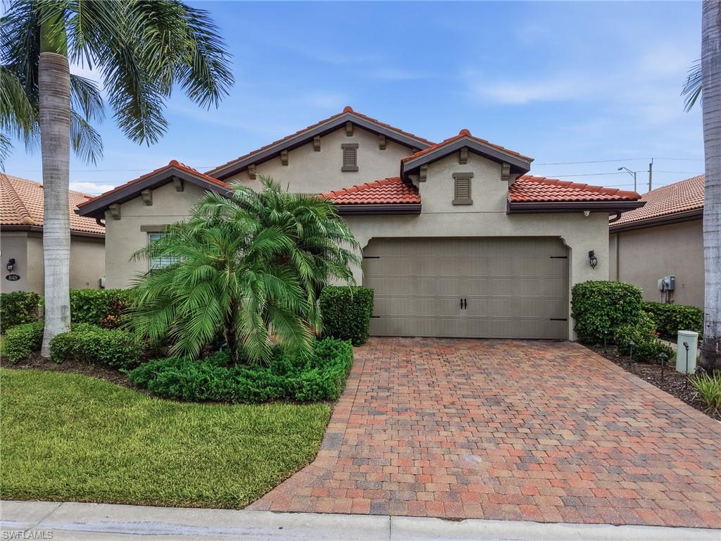 Mediterranean-style home featuring a red tile roof, stucco exterior, and a paver driveway
