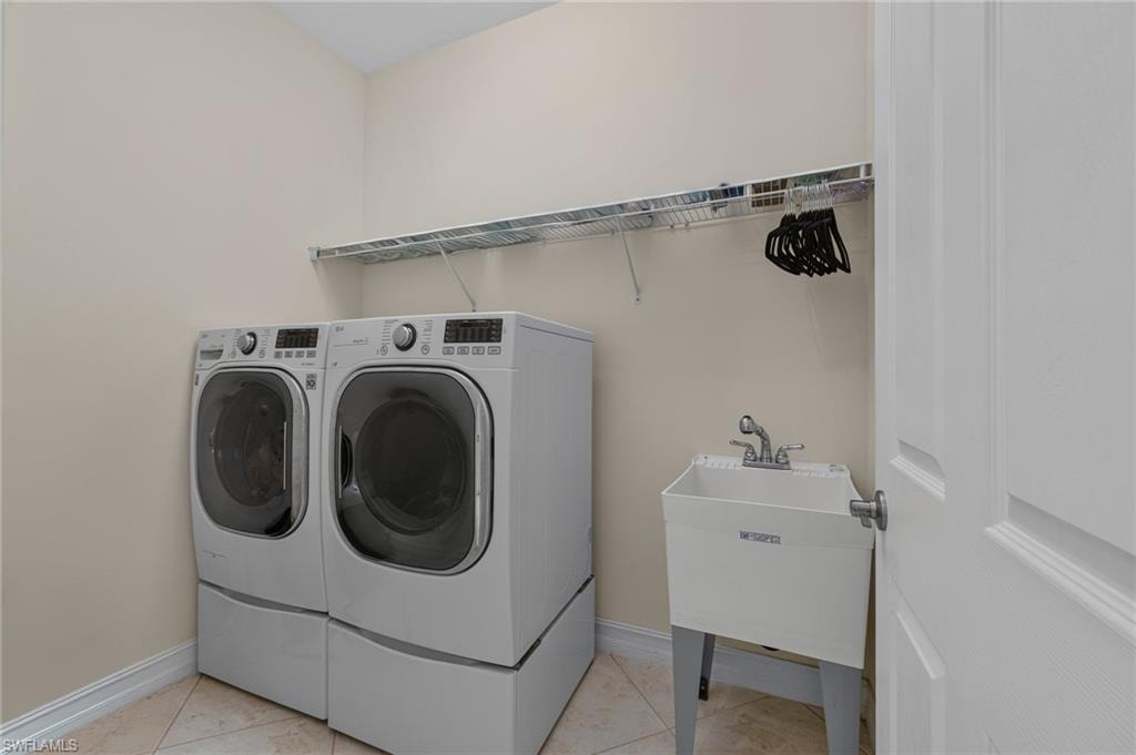 Dedicated utility room featuring floor-mounted laundry appliances, a utility sink with faucet, and wire shelving