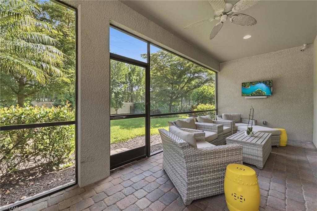 Screened patio featuring paver flooring, a textured stucco wall, and a ceiling fan