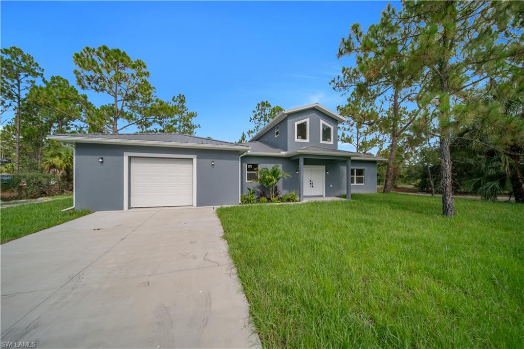 Contemporary home exterior featuring a two-story elevation, attached single-car garage, white garage door, concrete driveway, and a front lawn with mature trees