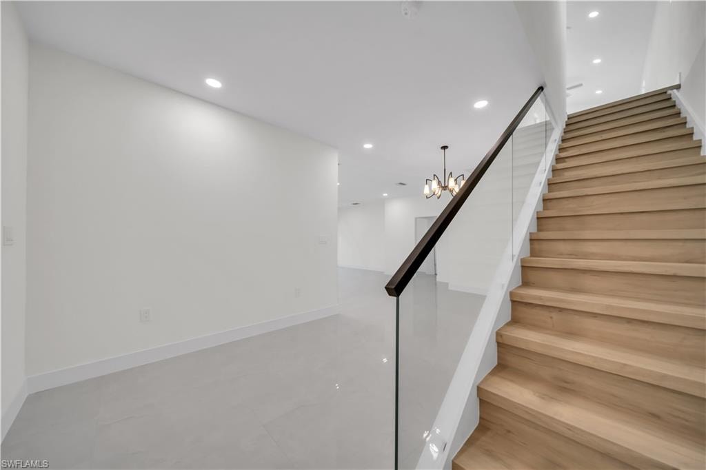 Hardwood staircase to the second floor with clear glass railing and dark-finish handrail
