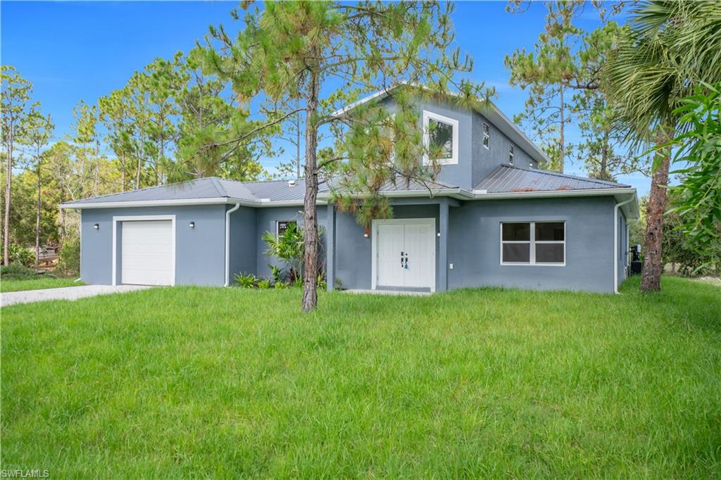 Two-story residence featuring a blue stucco exterior with a gray metal roof