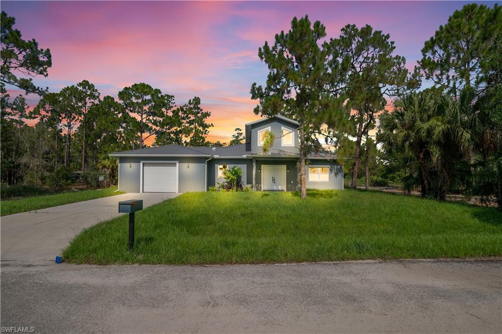 Contemporary single-family residence featuring a two-car garage, established front lawn, and mature trees