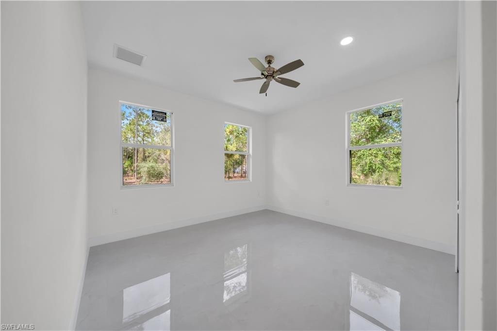 guest bedroom number two featuring three windows, a ceiling fan with integrated lighting, recessed lighting, and light-toned tile flooring