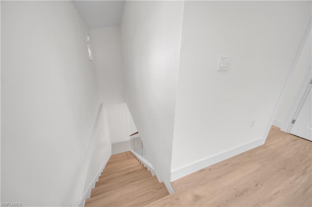 Staircase with light wood-finish treads, glass railing, and a minimalist wood handrail