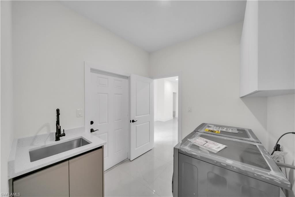Laundry area featuring a built-in utility sink with a matte black faucet, light-toned countertop, and base cabinetry