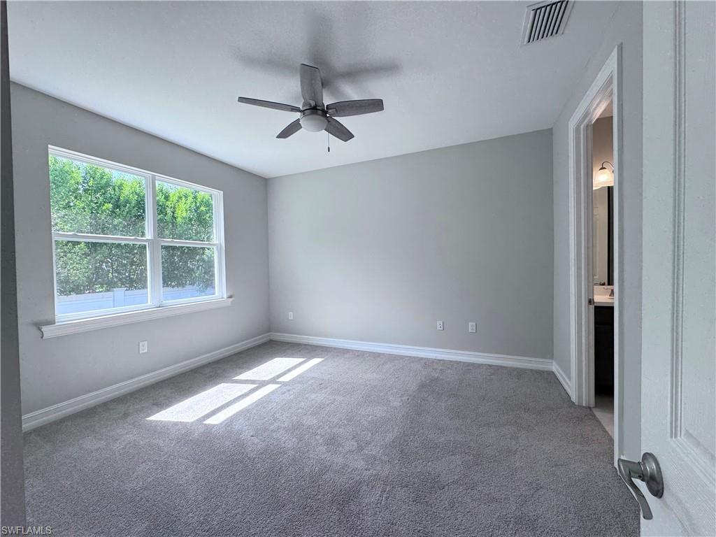 Carpeted spare room with baseboards and ceiling fan