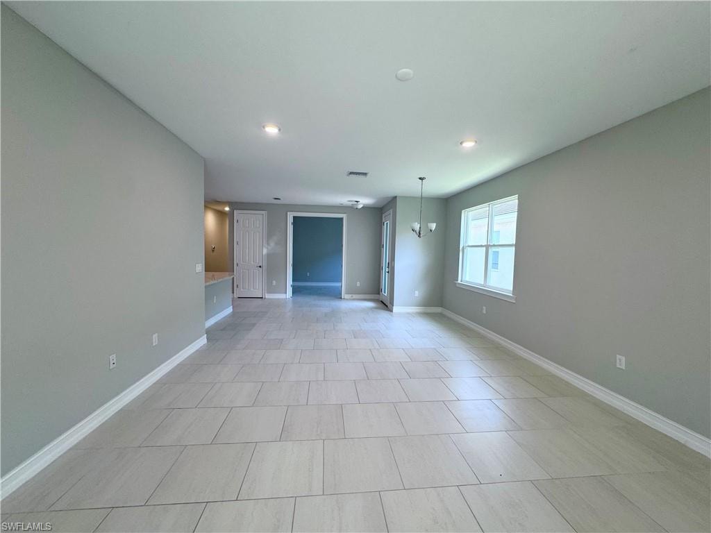 Unfurnished living room featuring a chandelier, recessed lighting, and light tile patterned floors