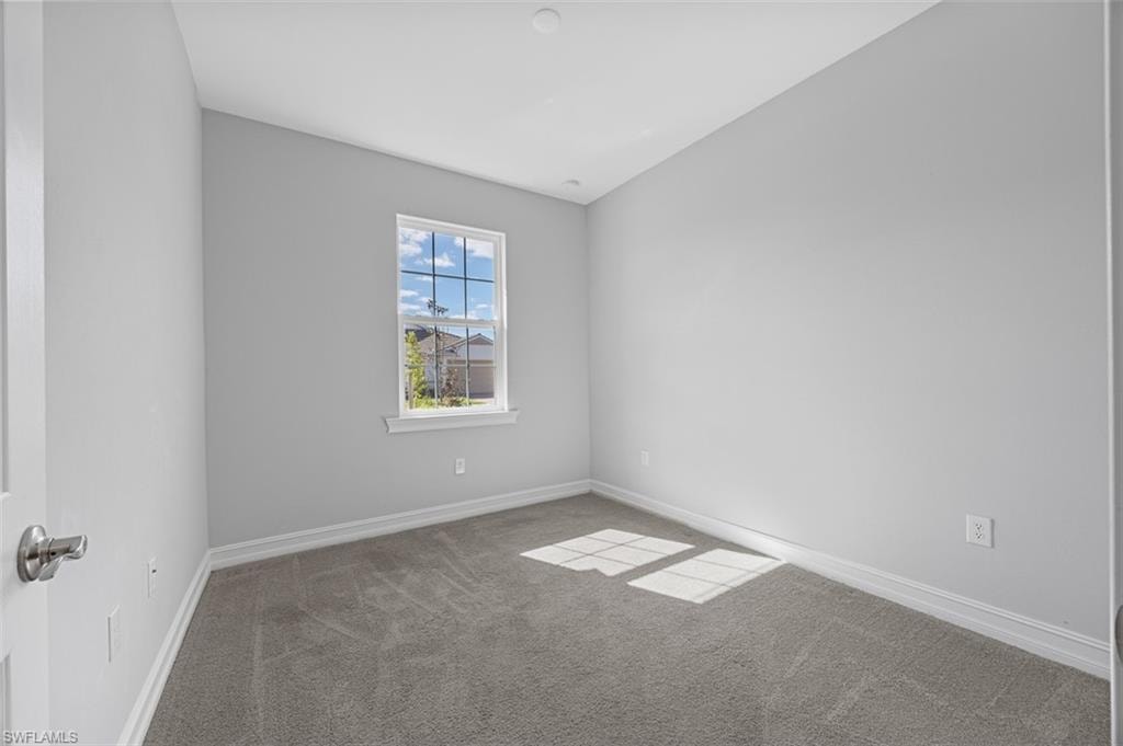 Carpeted spare room featuring baseboards