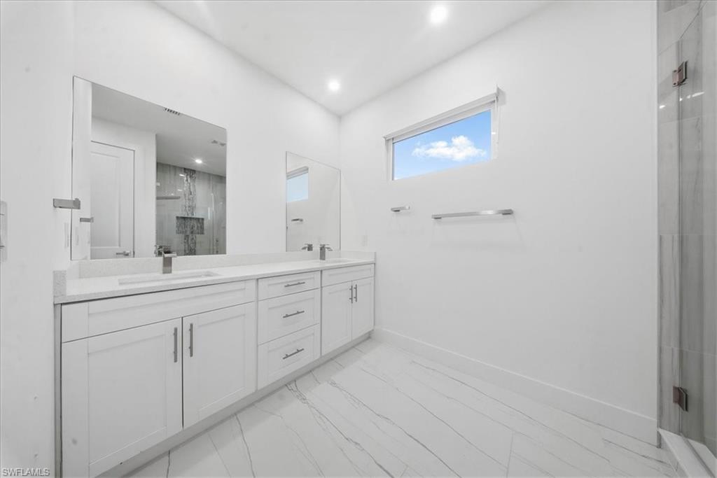 Dual vanity with white cabinetry, integrated sinks, and polished chrome fixtures