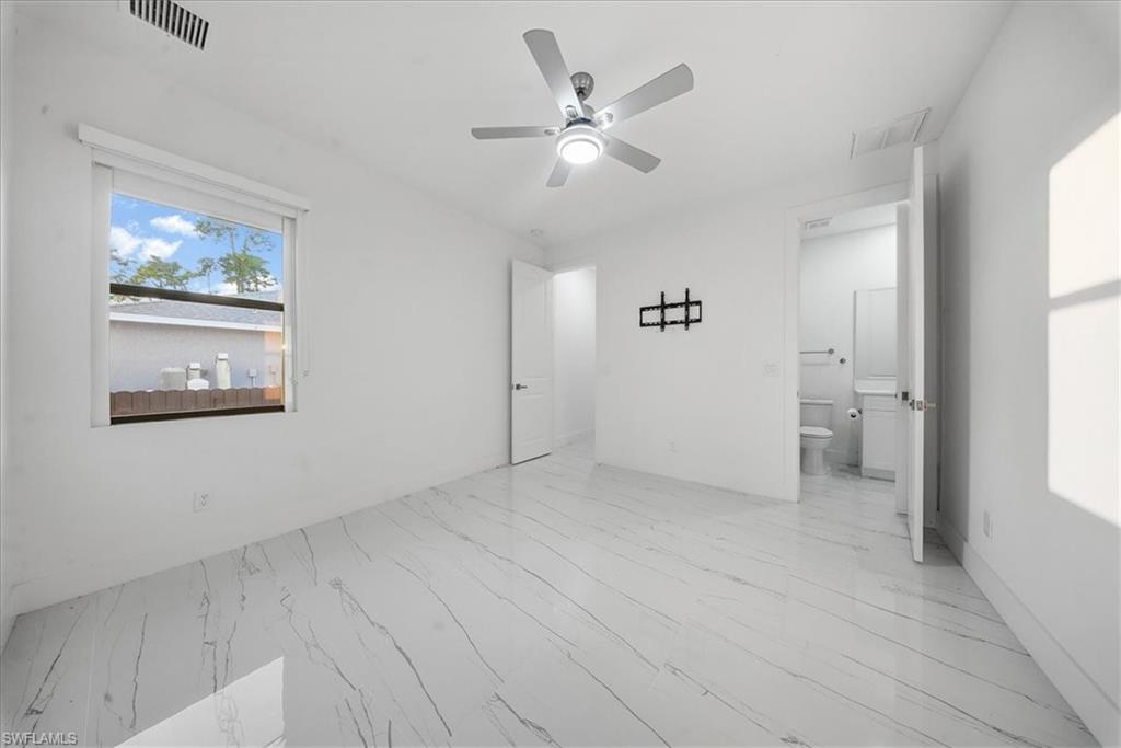 Spacious room featuring white walls, large window, and wood-finish flooring with a marble-like pattern