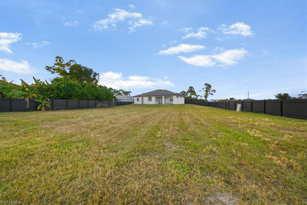 Expansive backyard featuring a large grass lawn, perimeter fencing, and a contemporary single-story residence in the background