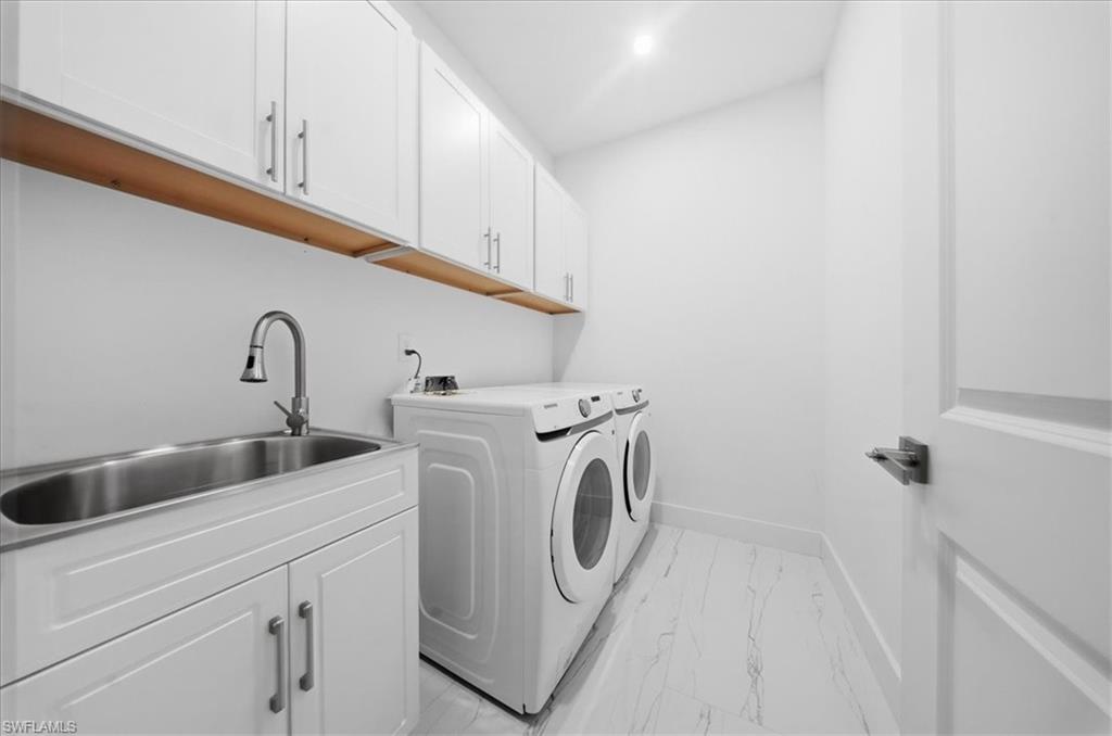 Dedicated laundry area featuring white shaker-style cabinetry, a stainless steel utility sink with a pull-down faucet, a light wood-finish shelf, and contemporary flooring