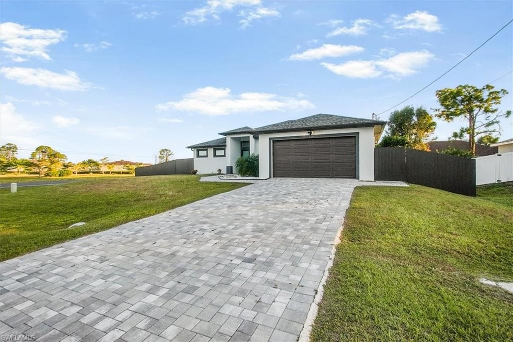 Contemporary single-story residence with a paver driveway, dark brown garage door, and a contrasting dark fence bordering the property