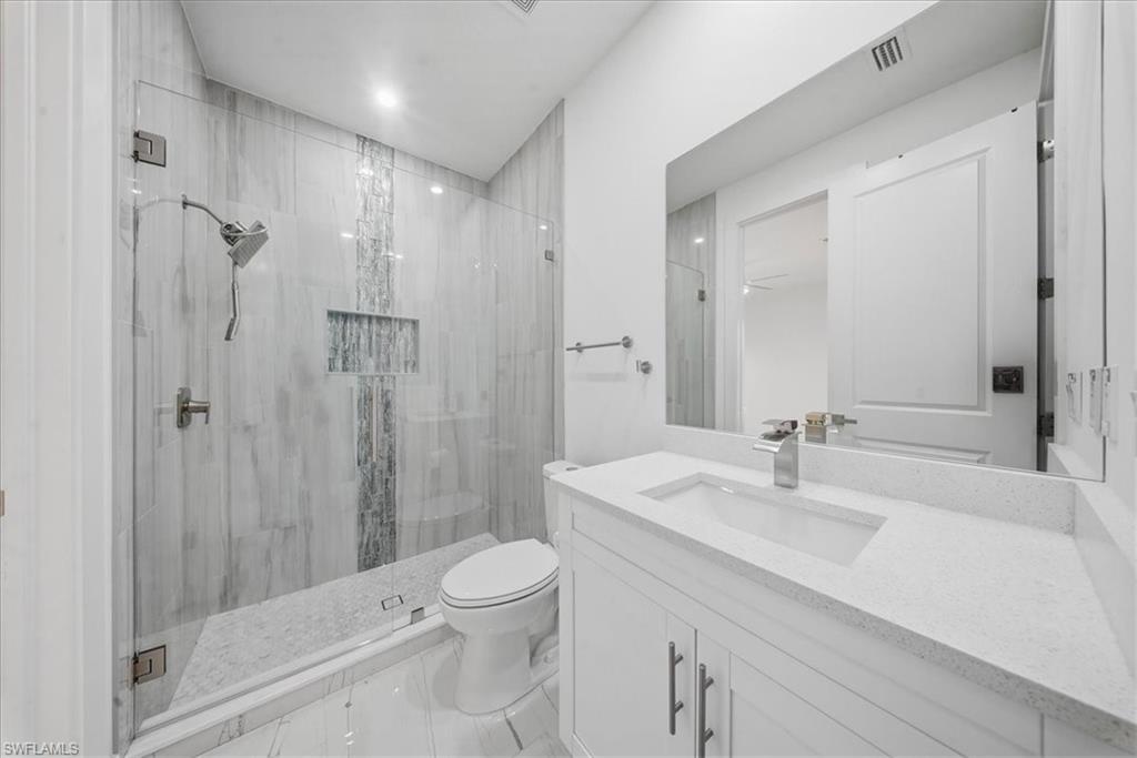Modern bathroom featuring a glass-enclosed shower with tile surround and an integrated niche