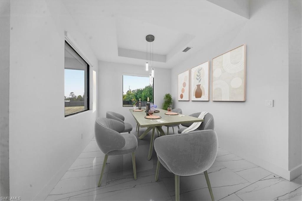 Open dining area featuring large format tile flooring and a tray ceiling