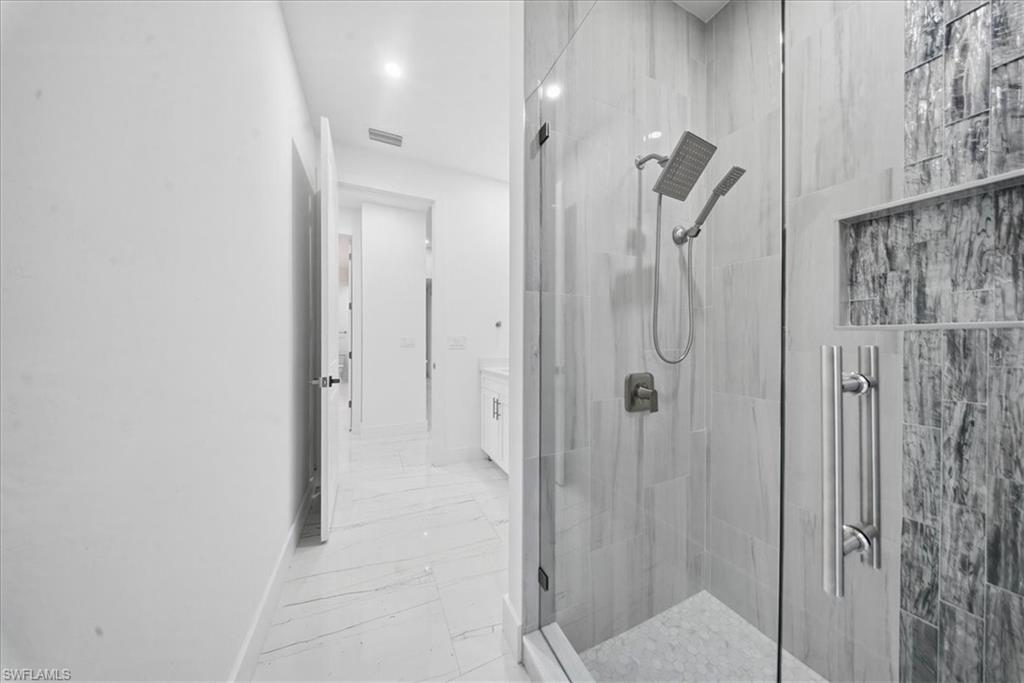 Spacious shower enclosure with clear glass door, dual shower heads, and an integrated recessed shelf