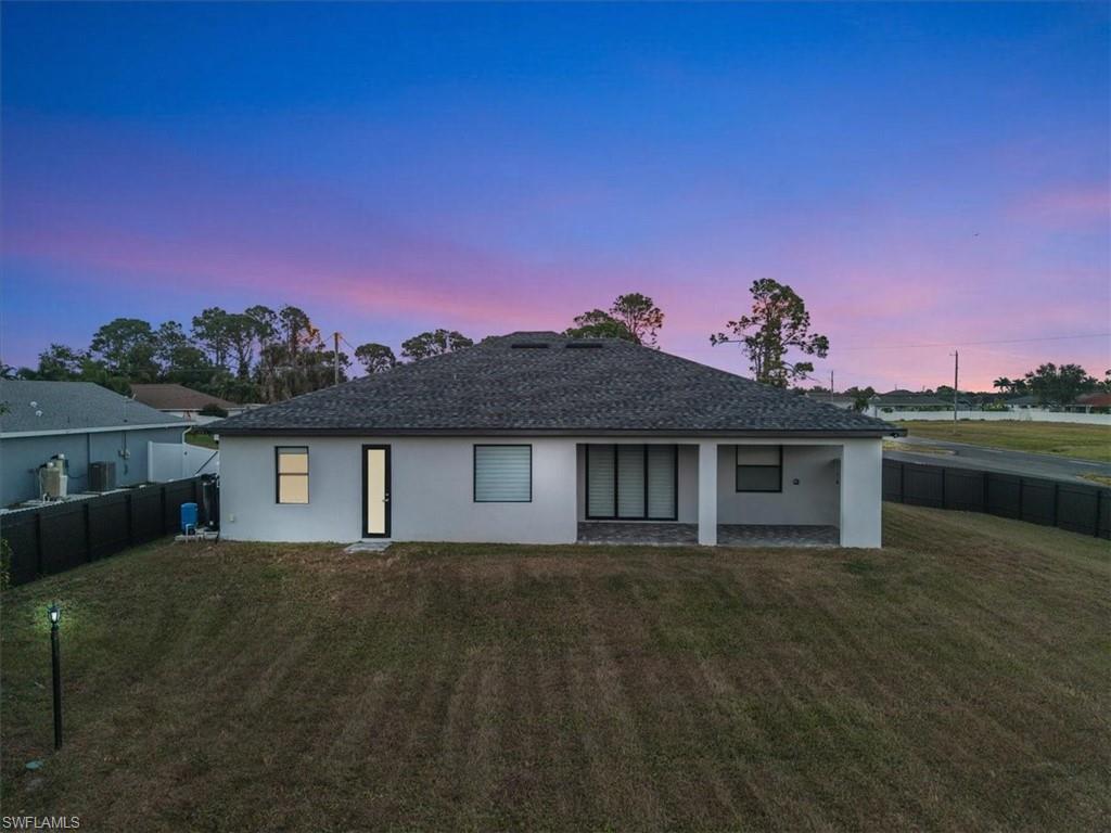 Contemporary rear exterior featuring a covered patio, expansive backyard, and privacy fencing