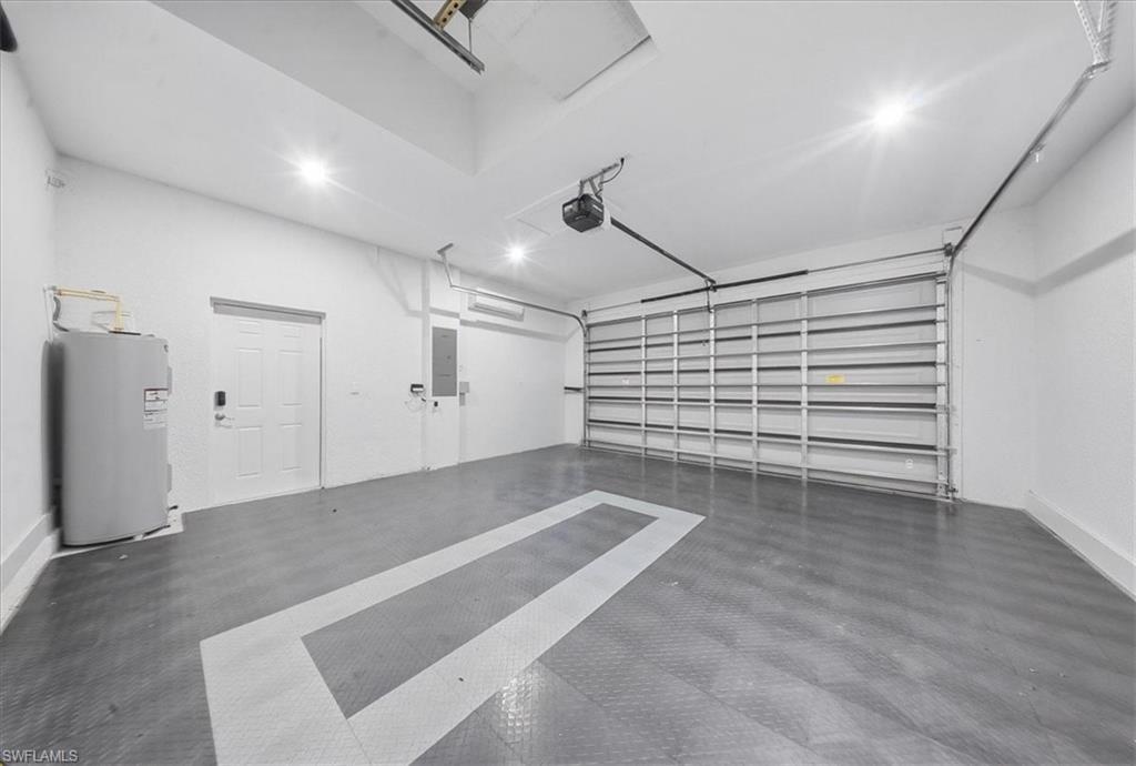 Spacious garage featuring a grey modular floor system with white accent lines, white interior walls, and an automatic garage door opener