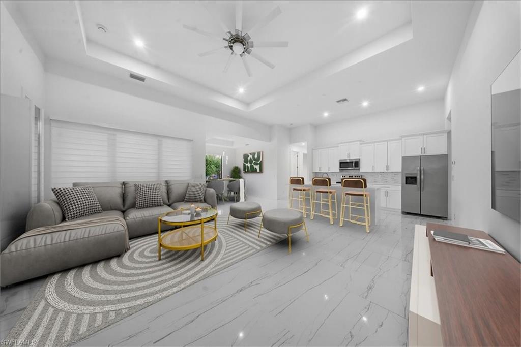 Open-concept living space featuring high ceilings with recessed lighting, an integrated kitchen island with seating, a full suite of stainless steel appliances, and large windows with horizontal blinds
