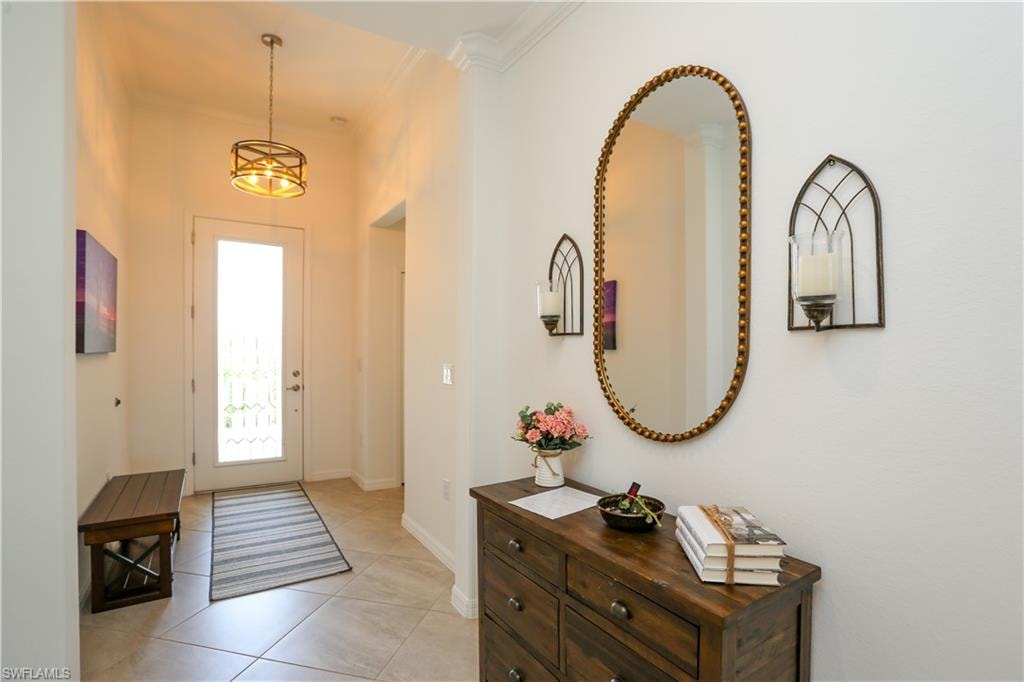 Foyer entrance featuring crown molding, light tile patterned flooring, and a notable chandelier