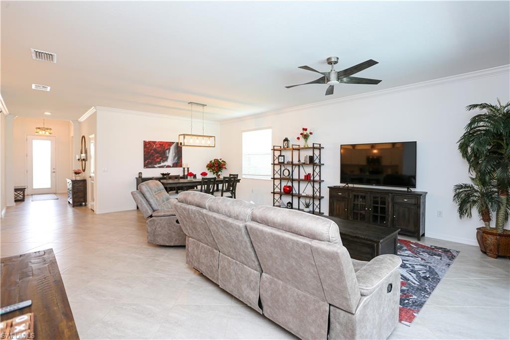 Tiled living room featuring crown molding, ceiling fan, and a wealth of natural light