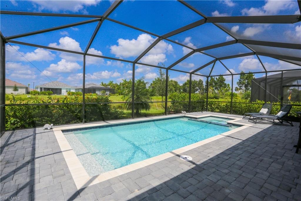View of swimming pool with glass enclosure and a patio area