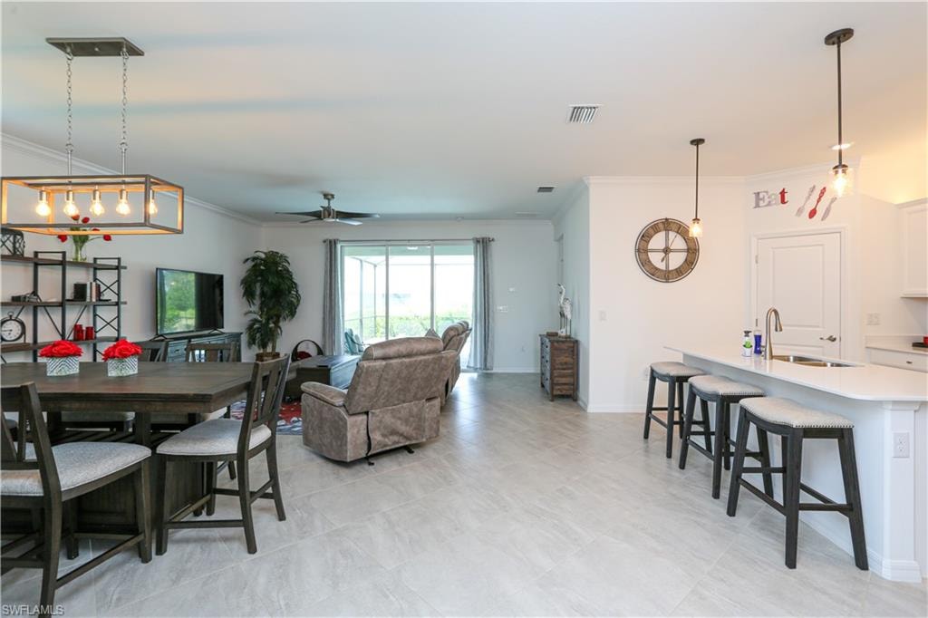 Dining room featuring ceiling fan, crown molding, and sink