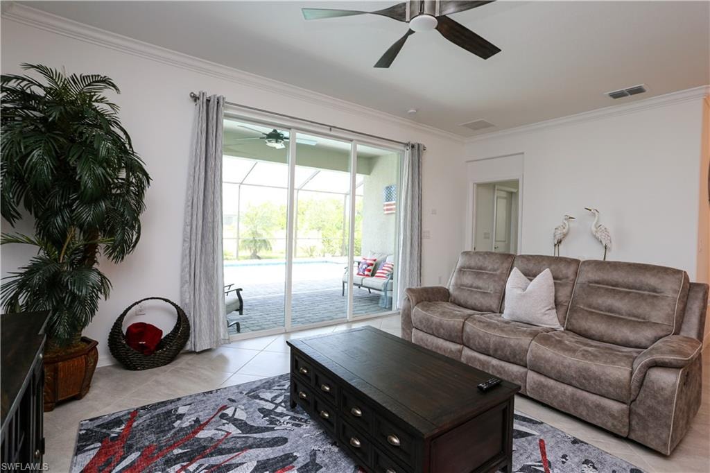 Tiled living room featuring ceiling fan and ornamental molding