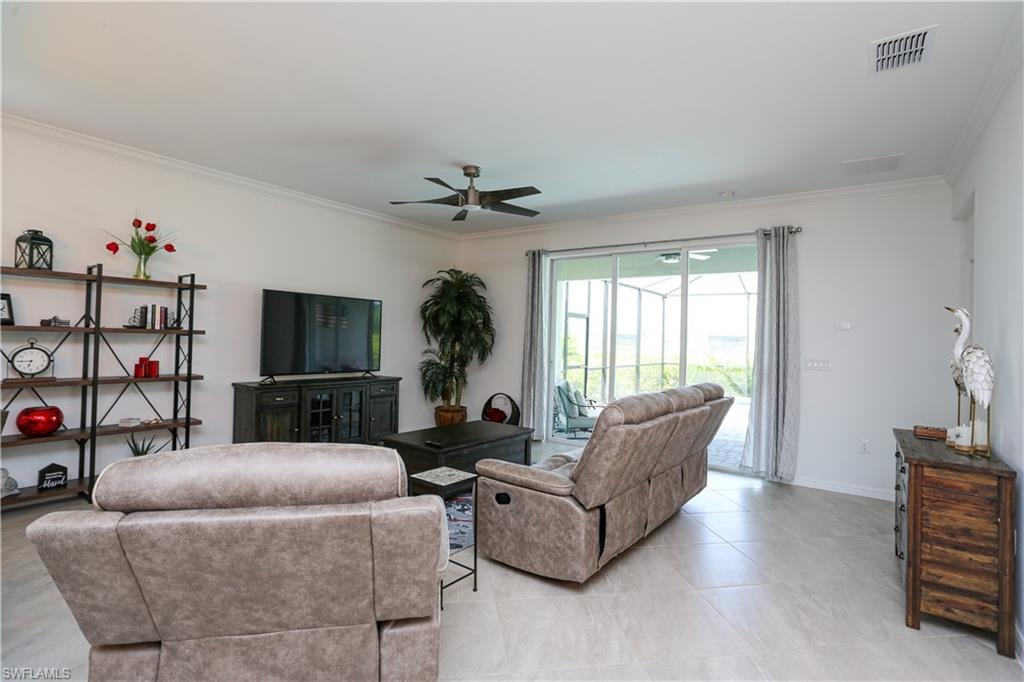 Living room with ornamental molding, ceiling fan, and light tile patterned floors