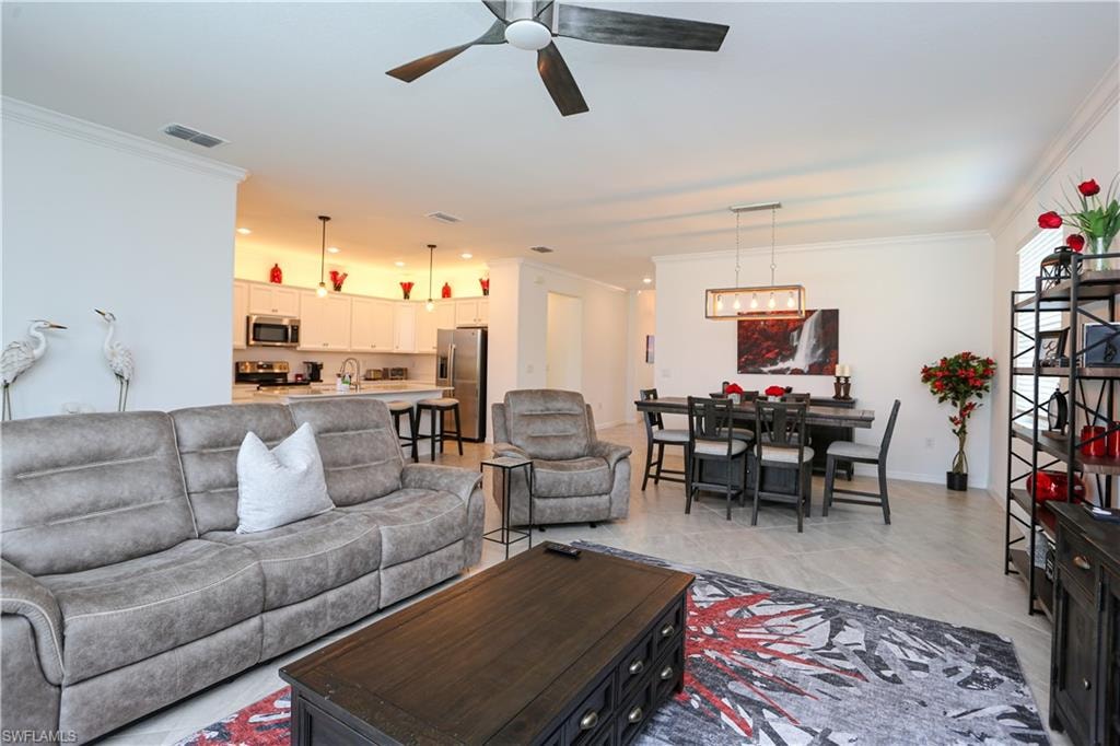 Living room with ceiling fan with notable chandelier and ornamental molding