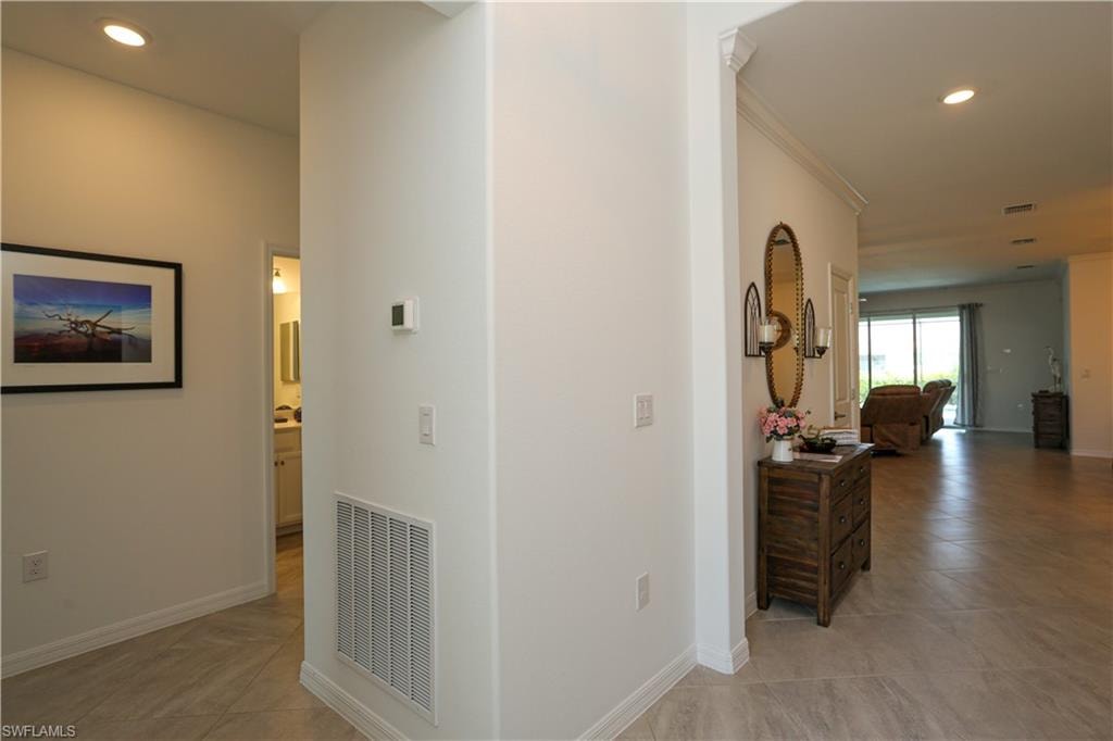 Hallway with ornamental molding and light tile patterned floors