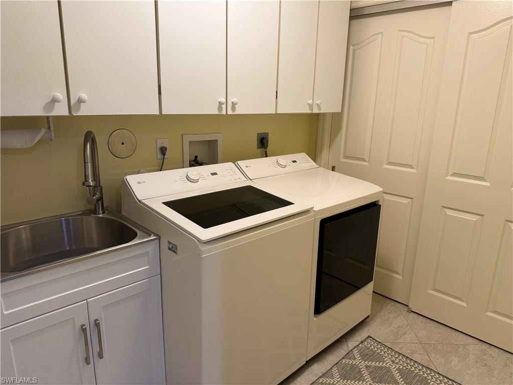 Washroom with cabinet space, separate washer and dryer, and light tile patterned floors