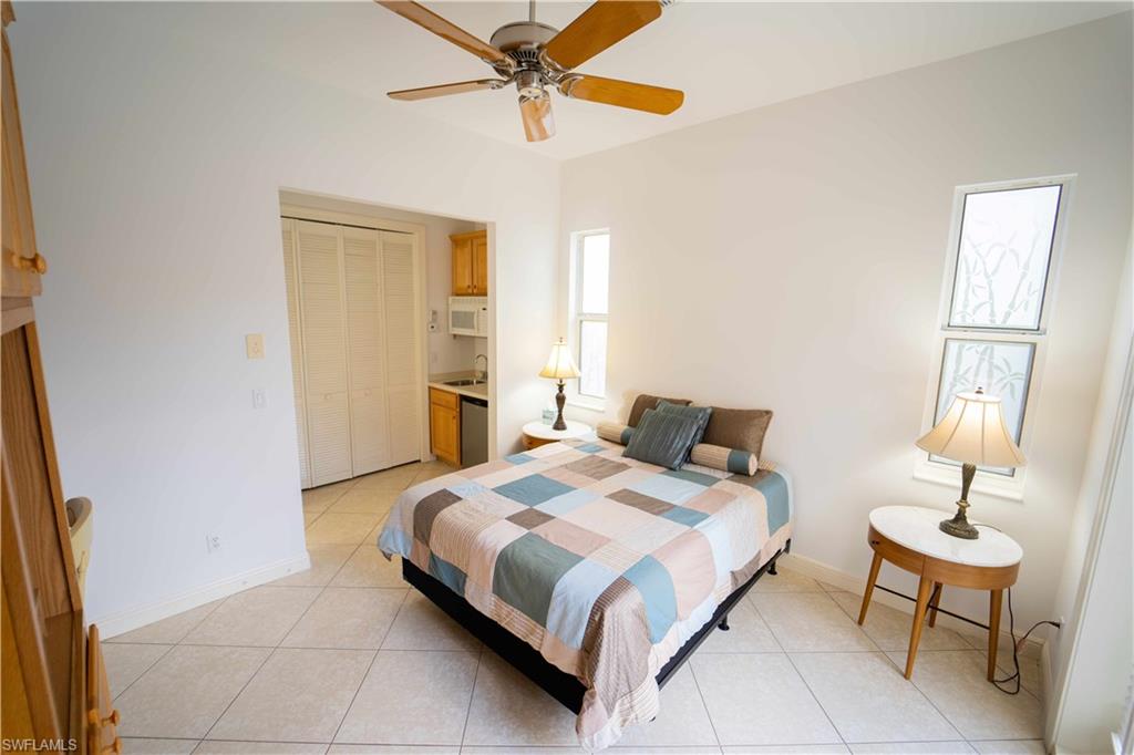 Tiled bedroom with ceiling fan and sink
