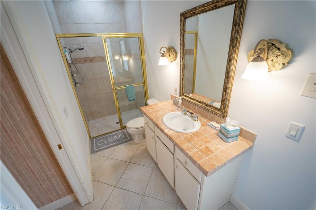 Bathroom featuring tile patterned flooring, walk in shower, vanity, and toilet