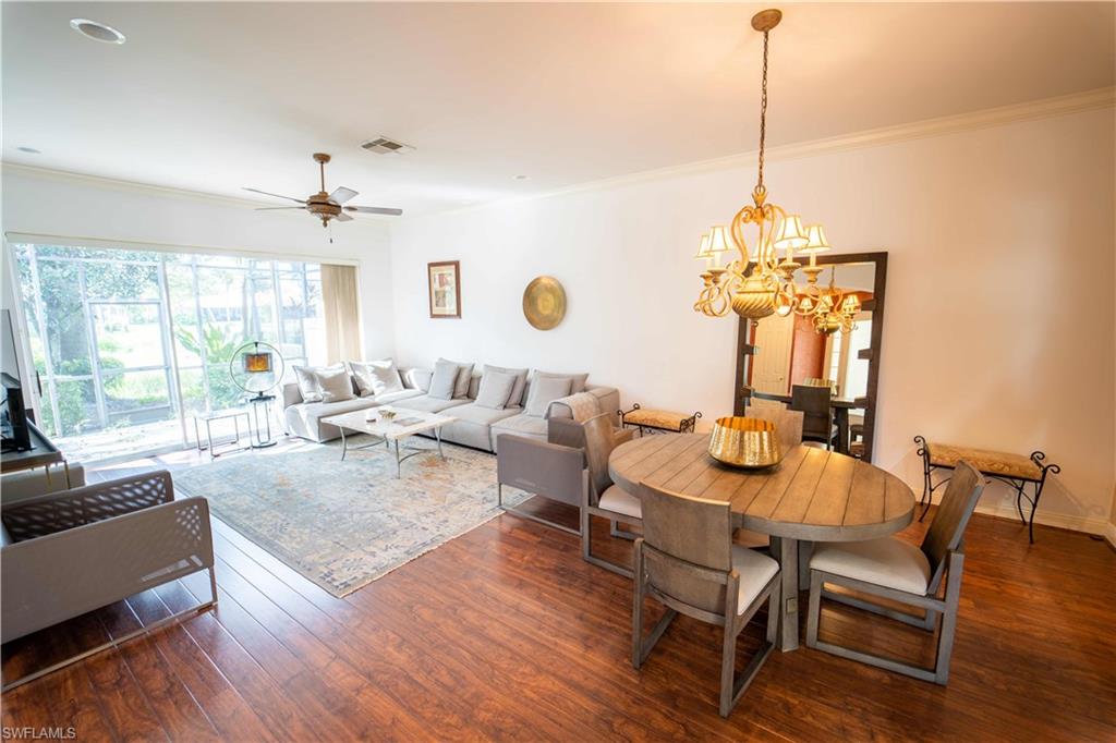 Dining space featuring ceiling fan with notable chandelier, crown molding, and dark wood-type flooring