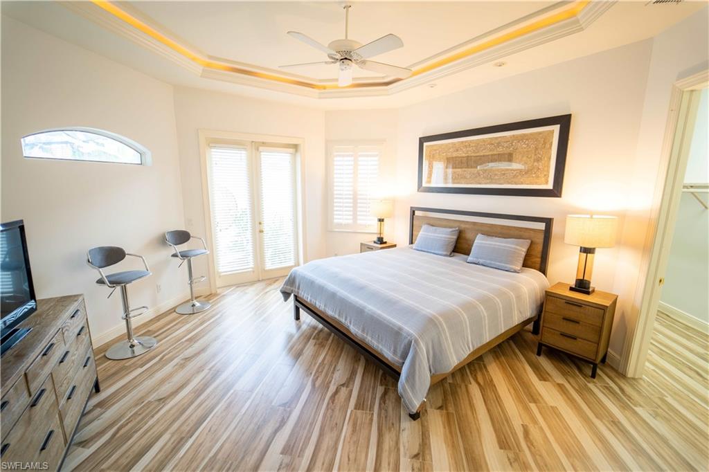 Bedroom with a raised ceiling, ornamental molding, ceiling fan, and light hardwood / wood-style flooring