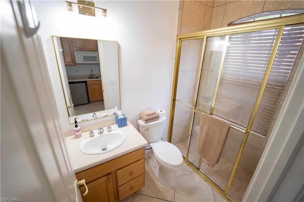 Bathroom featuring tile patterned floors, a shower with door, vanity, and toilet