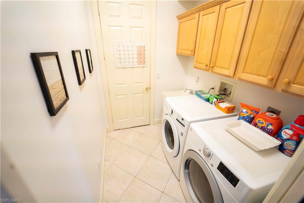Washroom featuring light tile patterned floors, independent washer and dryer, and cabinets