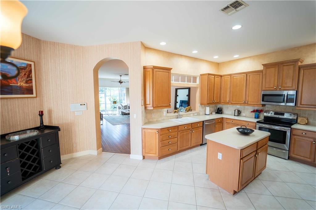 Kitchen with light wood-type flooring, a center island, sink, stainless steel appliances, and ceiling fan
