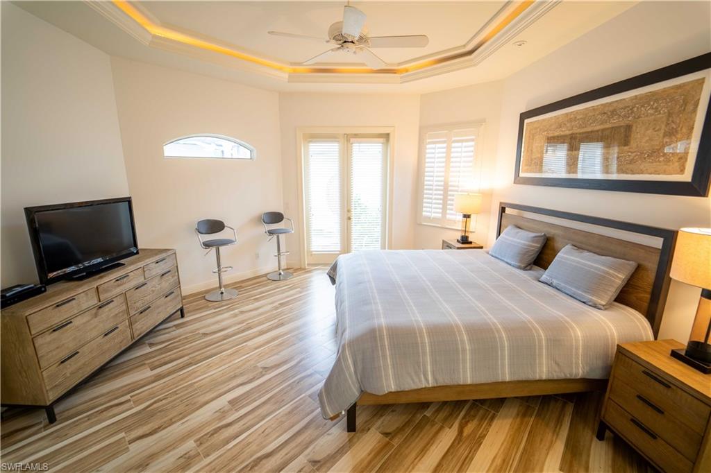 Bedroom featuring a raised ceiling, crown molding, ceiling fan, and light hardwood / wood-style flooring