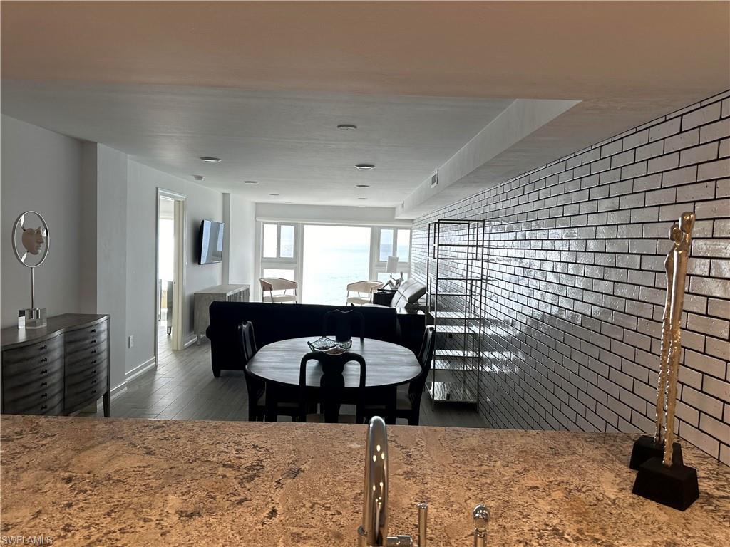 Dining room with brick wall and dark hardwood / wood-style floors