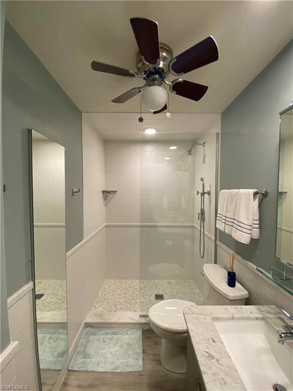 Bathroom with vanity, toilet, ceiling fan, and a tile shower