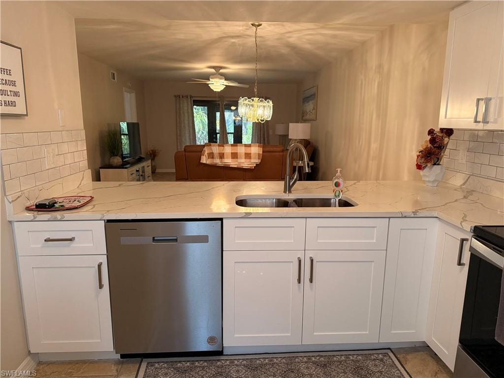 Kitchen featuring white shaker-style cabinetry with dark hardware, a stainless steel undermount sink with a gooseneck faucet, and light-toned countertops with veining