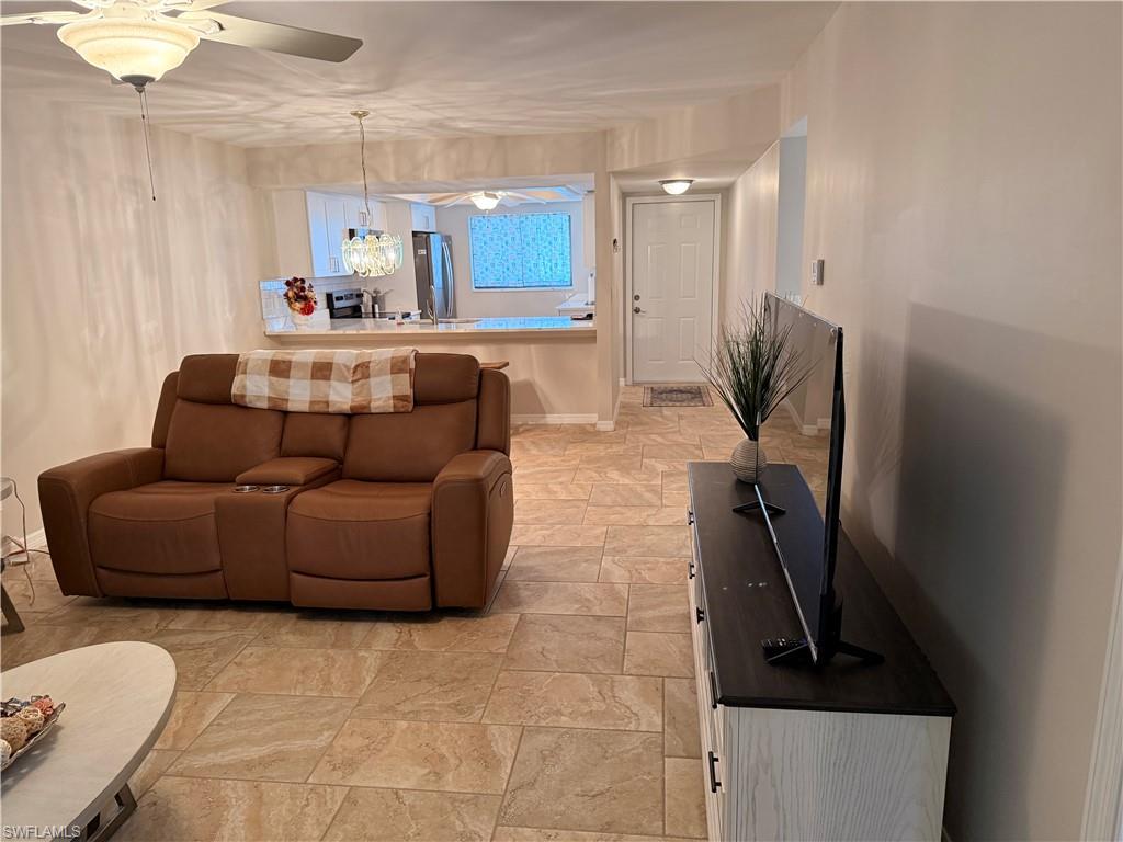 Open-concept living area featuring neutral tile flooring, a ceiling fan with integrated lighting, and recessed overhead lighting