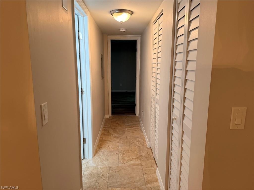 Hallway featuring patterned tile flooring, louvered bi-fold closet doors, and recessed ceiling lighting