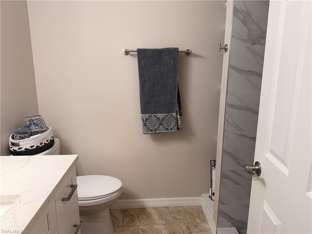 Bathroom featuring a light-toned vanity with a stone countertop, a white toilet, and neutral wall paint